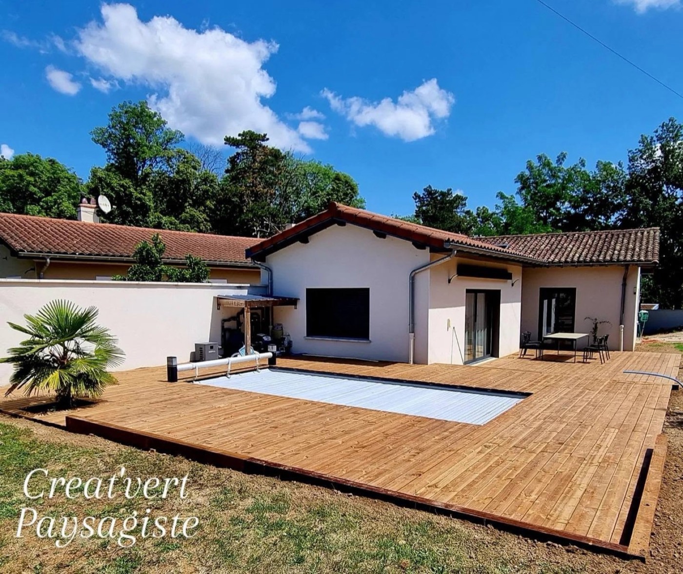 Grande terrasse en bois autour d'une piscine, devant une maison