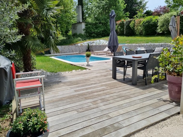 Terrasse en bois et salon au bord d'une piscine